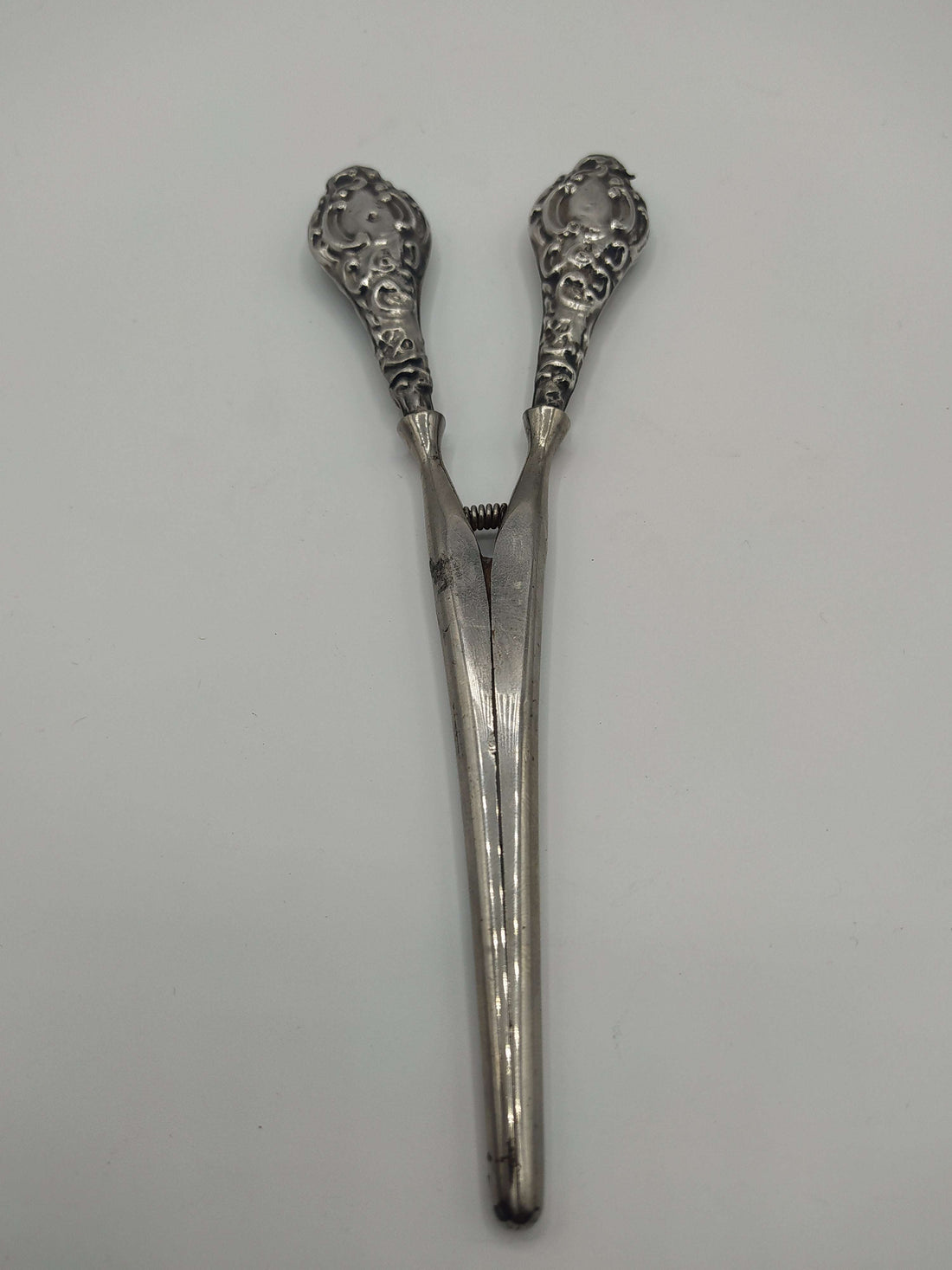 Pinza para guantes en plata de ley con diseño ornamentado y acabado vintage. Ideal para decoración elegante en el hogar o colección antigua.