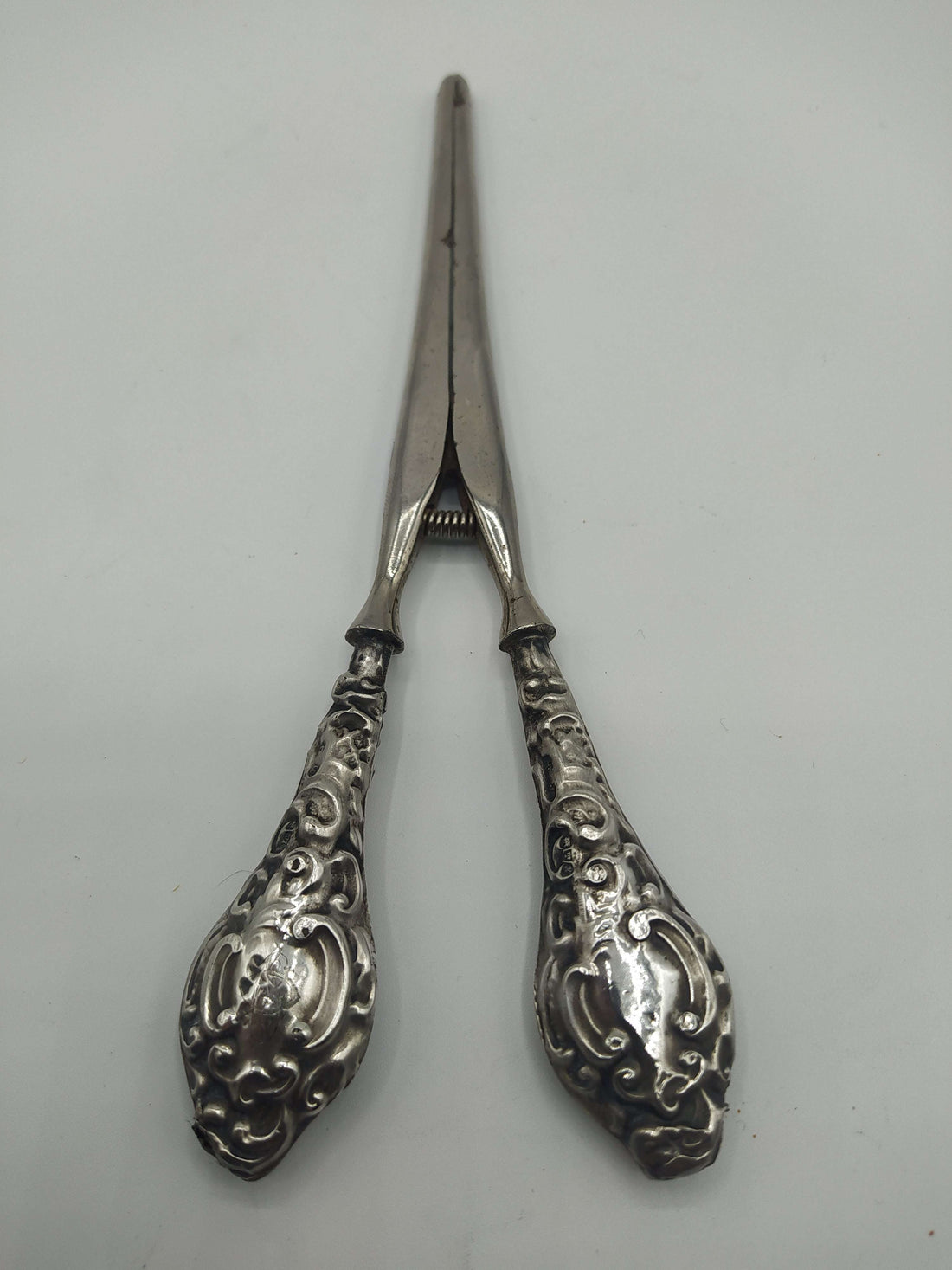 Pinza para guantes en plata de ley con diseño ornamentado y acabado vintage. Ideal para decoración elegante en el hogar o colección antigua.