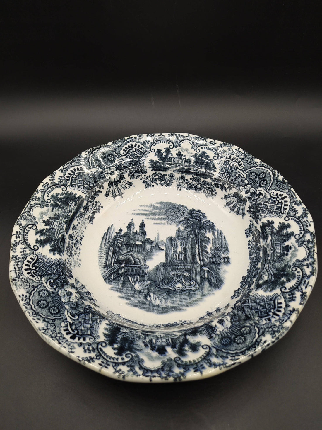 Plato hondo de porcelana La Cartuja, modelo vistas, siglo XIX, con decoración en negro de paisajes clásicos y borde ornamentado. Ideal para decoración vintage.