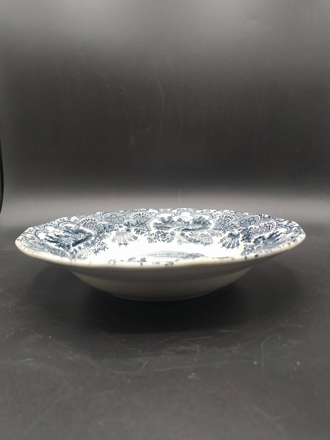 Plato hondo de porcelana La Cartuja, modelo vistas, siglo XIX, con decoración en negro de paisajes clásicos y borde ornamentado. Ideal para decoración vintage.