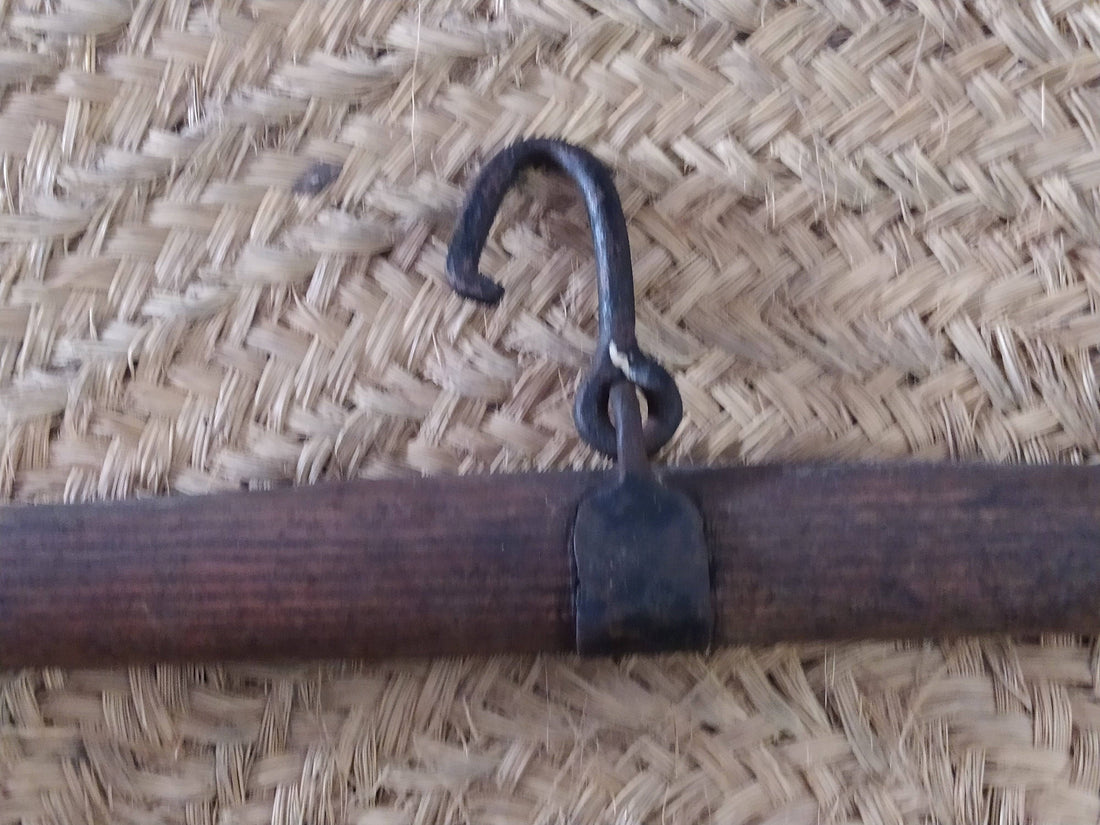 Balancín de madera dura para tiro animal con gancho central y extremos metálicos, ideal para mulas y caballos en decoración rústica.