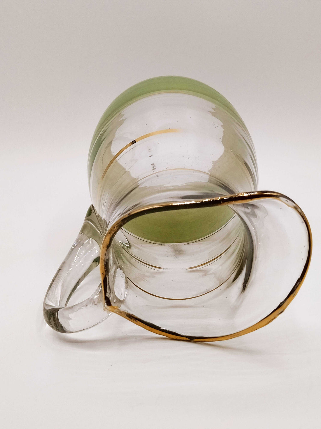 Jarra de cristal verde mate y dorado con acabado artesanal, ideal para decoración vintage en el hogar. Detalles dorados realzan su elegancia.