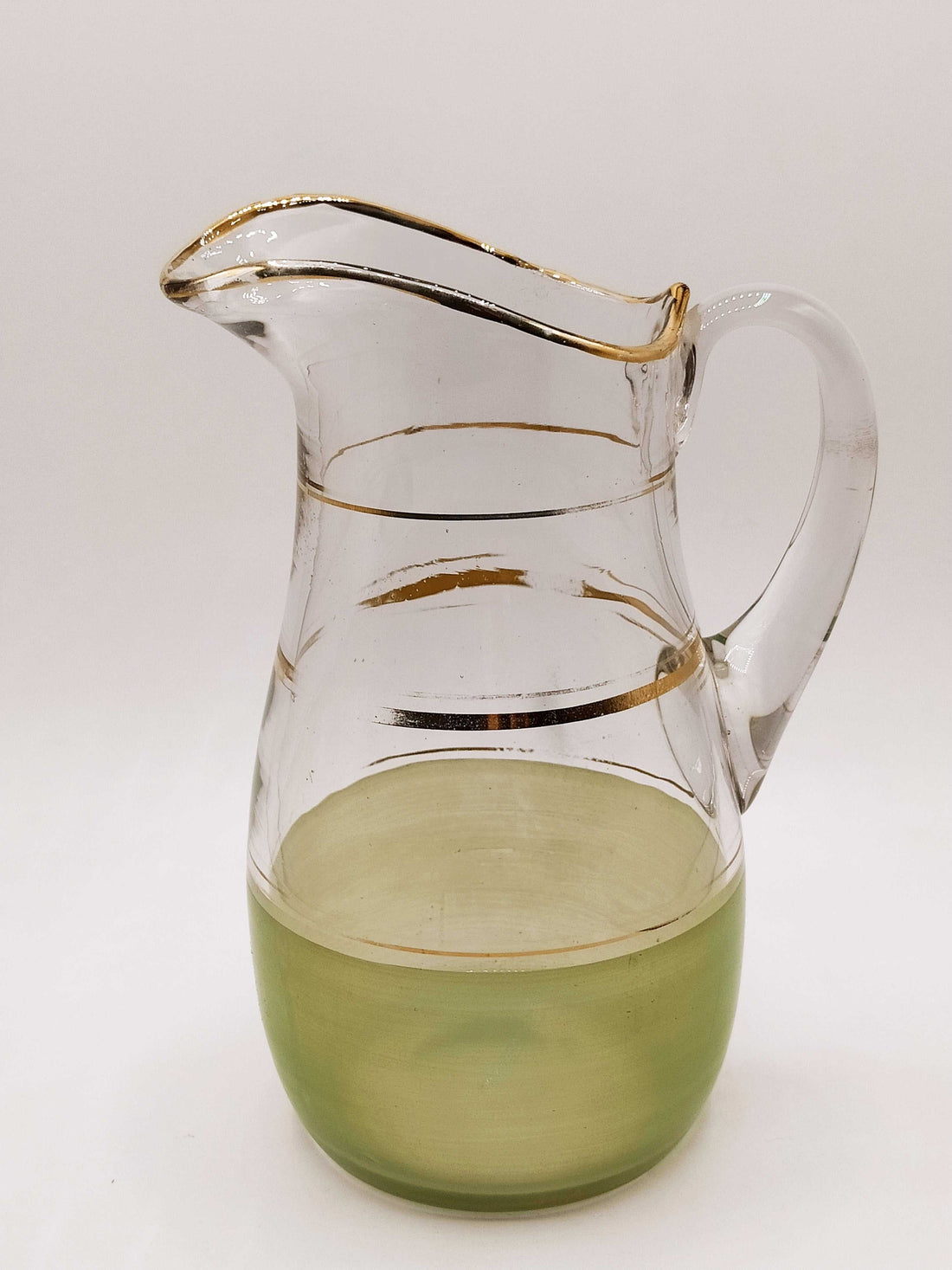 Jarra de cristal verde mate y dorado con acabado artesanal, ideal para decoración vintage en el hogar. Detalles dorados realzan su elegancia.