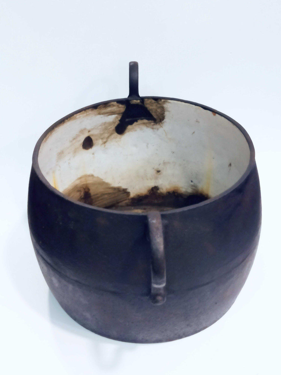 Olla de hierro antigua esmaltada con asas curvas, ideal para decoración vintage en cocinas rústicas o junto a chimeneas.