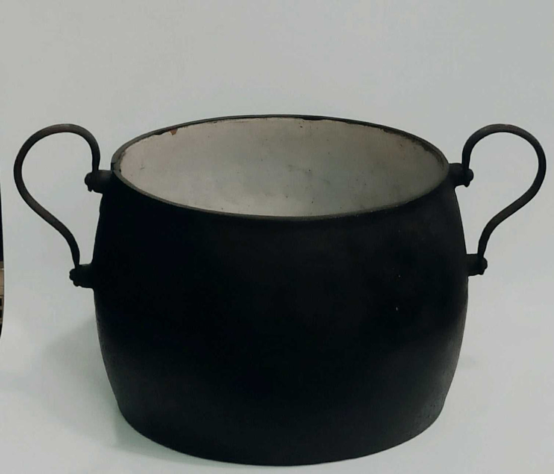 Olla de hierro antigua esmaltada con asas curvas, ideal para decoración vintage en cocinas rústicas o junto a chimeneas.