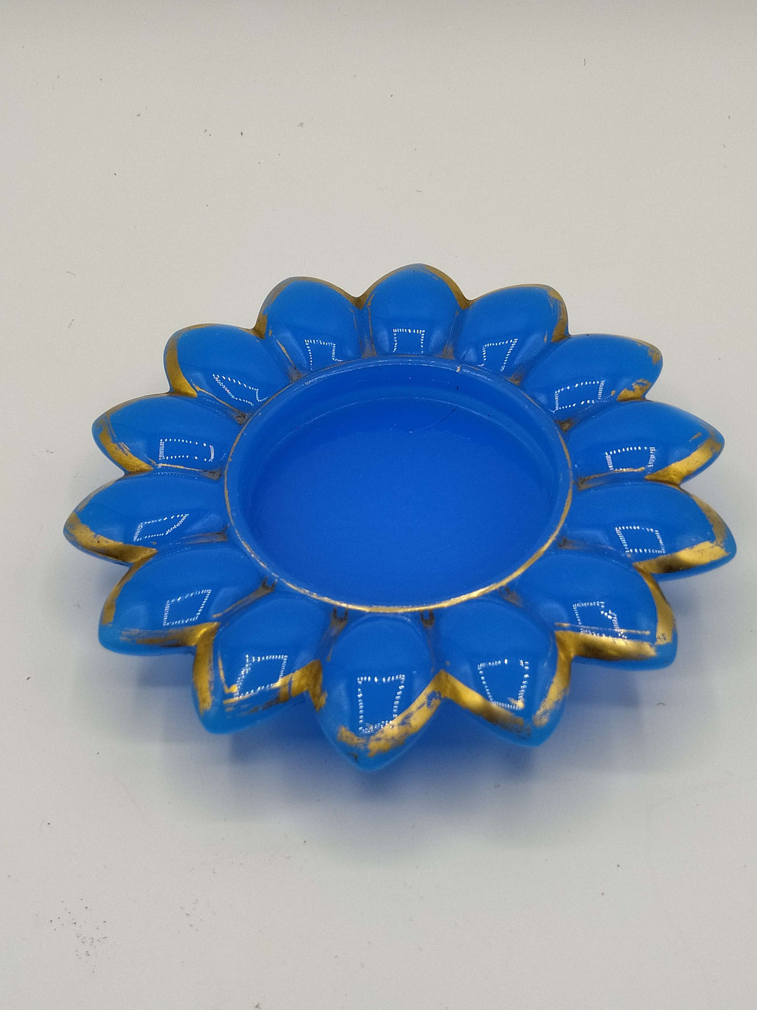 Plato de opalina azul con decorado dorado en forma de flor, ideal para decoración elegante en el hogar. Calidad premium, 14 cm de diámetro.