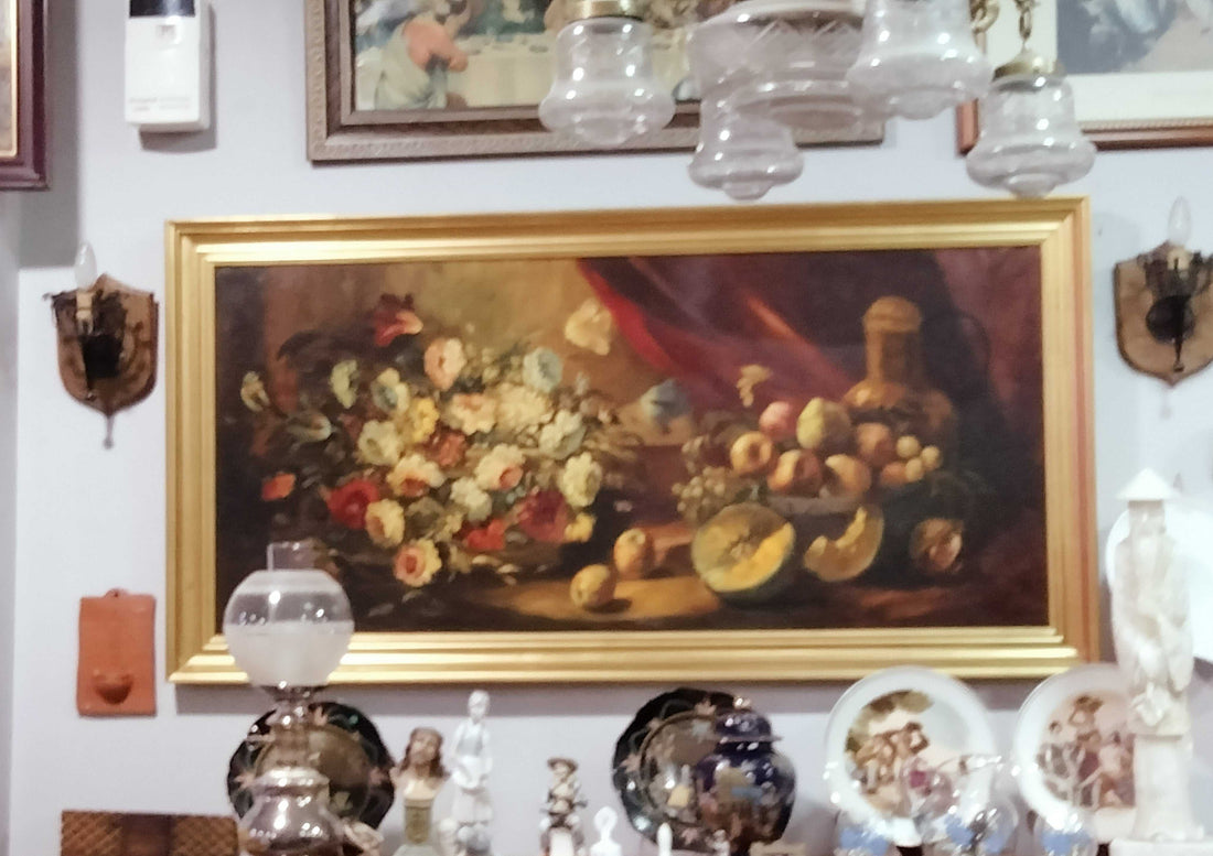 Bodegón en óleo sobre lienzo con marco dorado, firmado Ramírez, muestra flores, frutas y botella en estilo clásico. Ideal para decoración elegante.