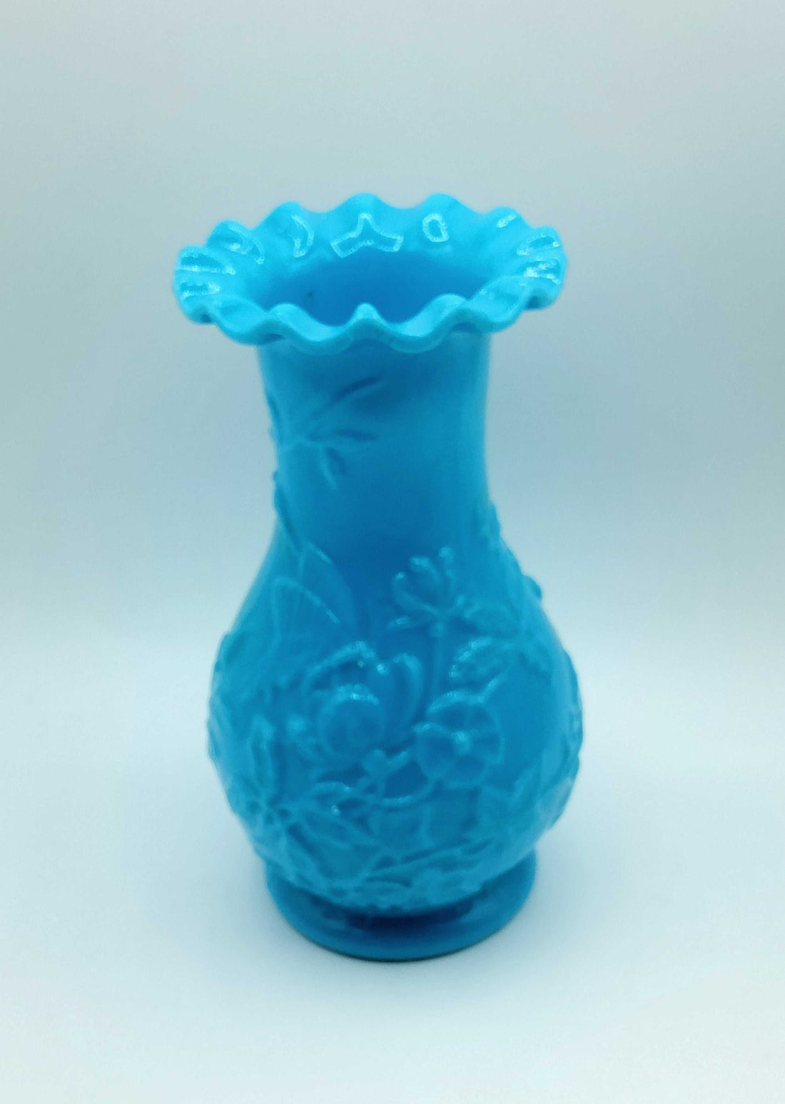 Jarrón de opalina azul con relieve floral, estilo vintage y acabado brillante, ideal para decoración elegante en el hogar.