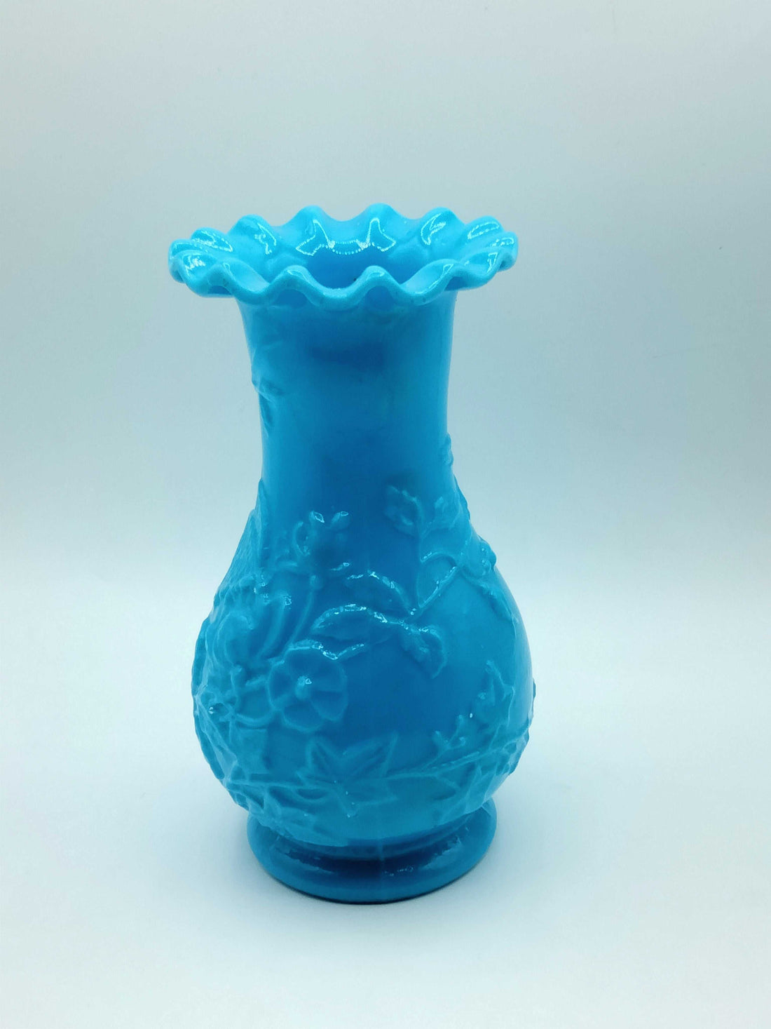 Jarrón de opalina azul con relieve floral, estilo vintage y acabado brillante, ideal para decoración elegante en el hogar.