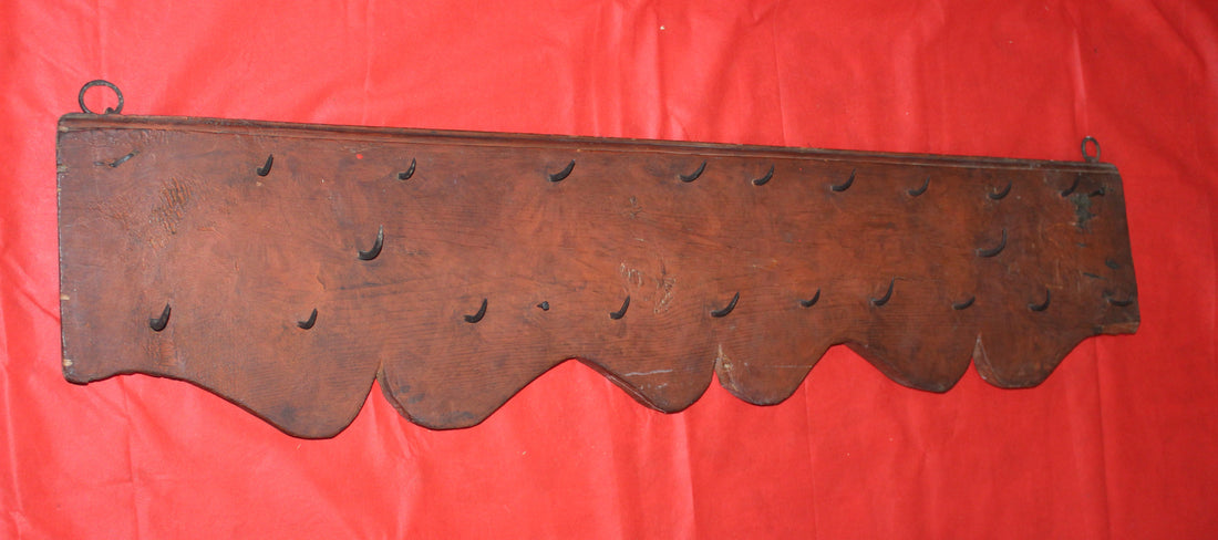 Percha antigua de matanzas con clavos de fragua, estilo rústico, hecha de madera oscura con ganchos forjados a mano. Ideal para decoración vintage en cocinas o salones de estilo rural.