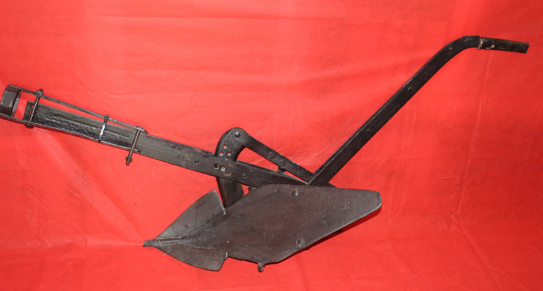 Antiguo arado de vertedera de tracción animal en hierro forjado, pieza decorativa rústica ideal para jardín o interiores vintage.