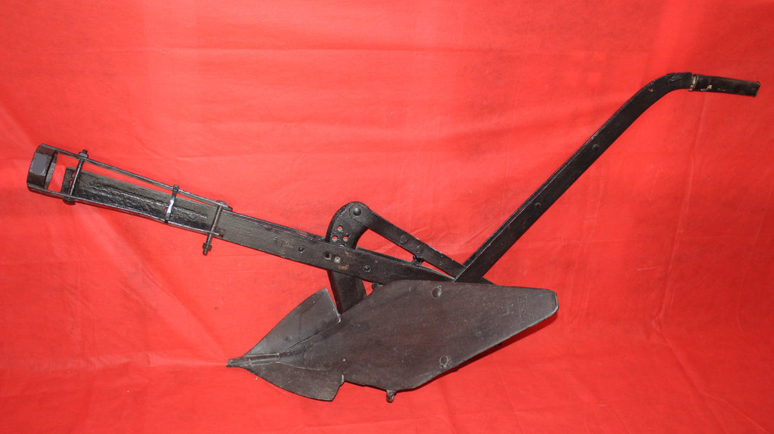 Antiguo arado de vertedera de tracción animal en hierro forjado, pieza decorativa rústica ideal para jardín o interiores vintage.