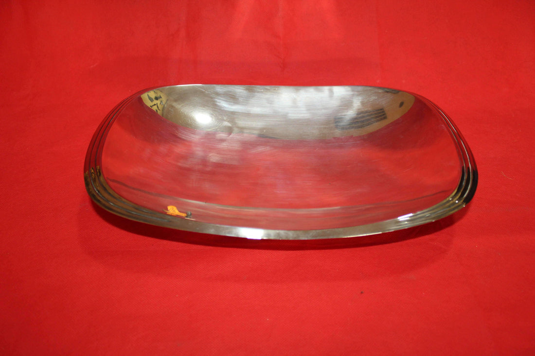 Bandeja con patas de metal plateado de alta calidad sobre fondo rojo, ideal para decoración de interiores o eventos especiales.