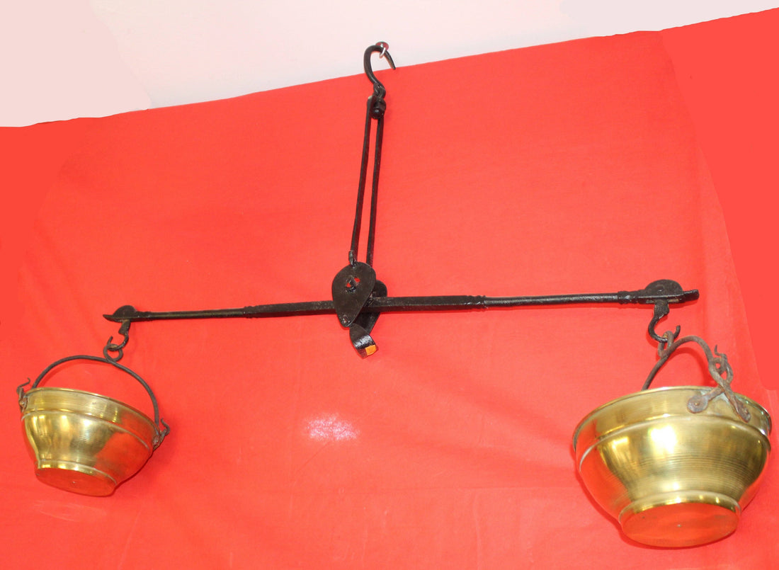 Balanza de hierro con cuencos de metal dorado sobre fondo rojo, decoración vintage ideal para el hogar. Excelente calidad y estilo antiguo.